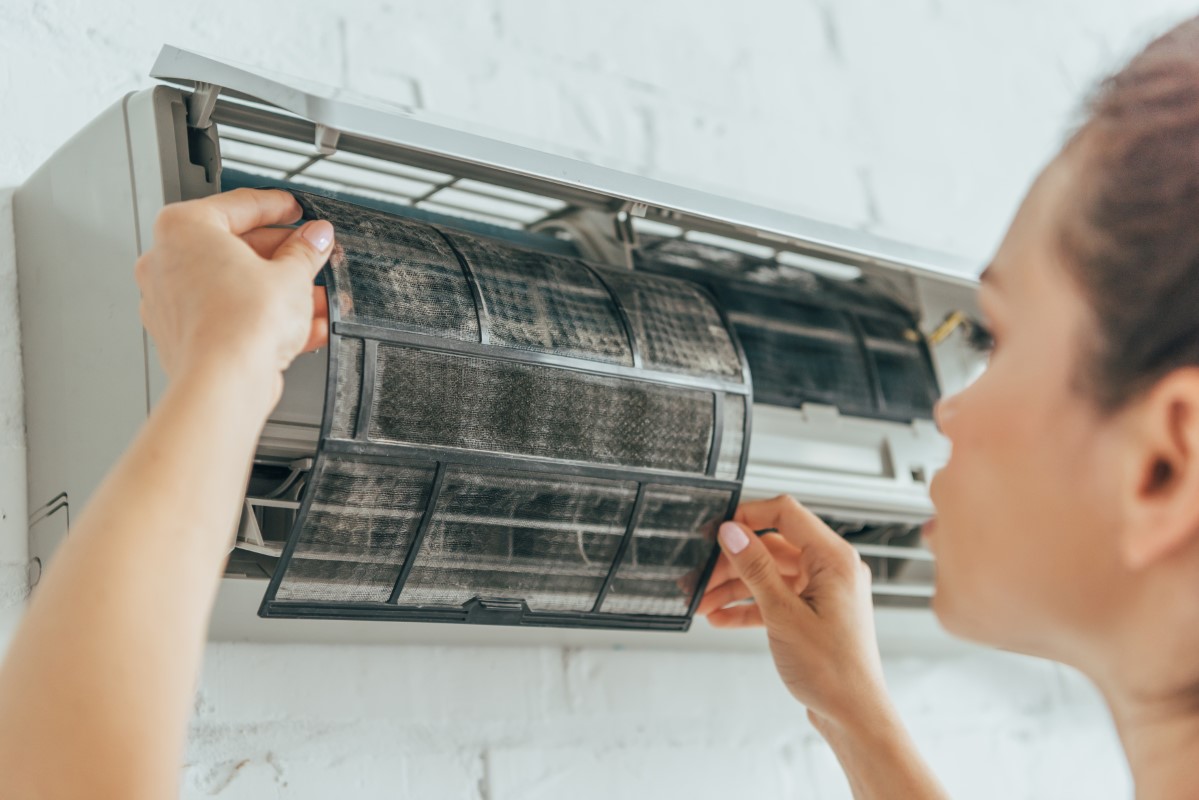 Mujer cambiando filtro para reparar aire acondicionado que no enfria bien